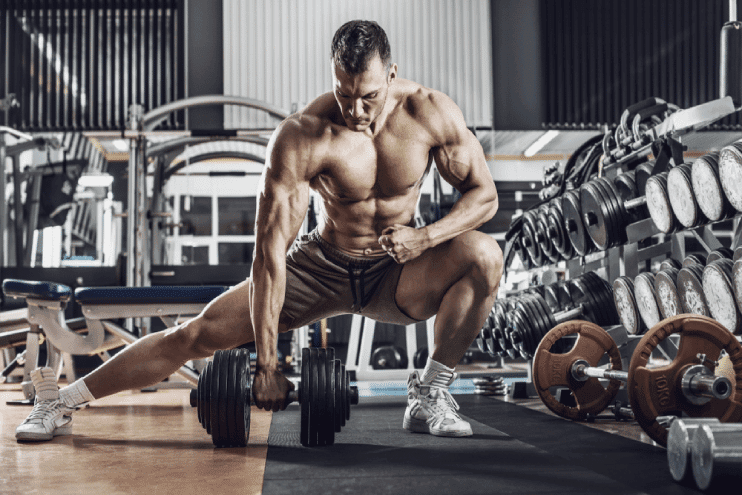focused male bodybuilder lifting a heavy dumbbell in the gym