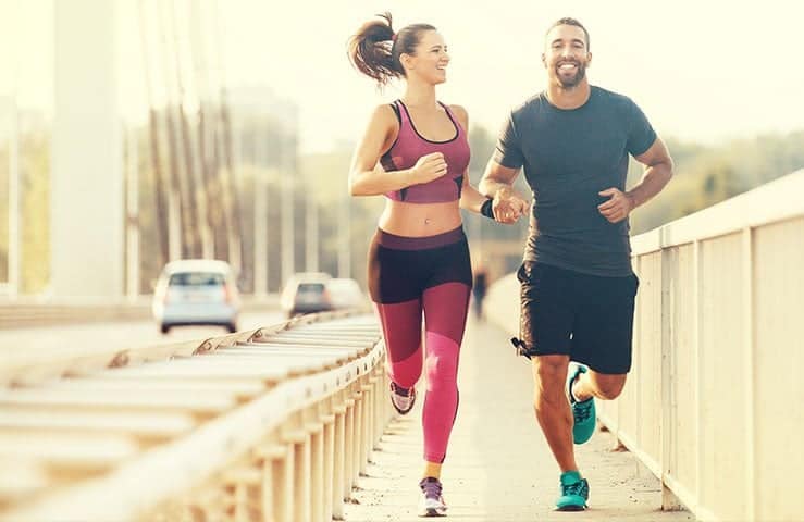 Young Couple Jogging Together And Smiling