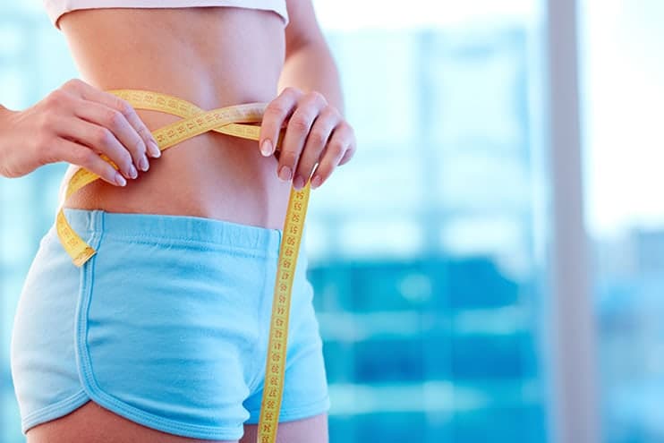 Woman In Blue Shorts And Tank Top Measuring Her Weight Loss