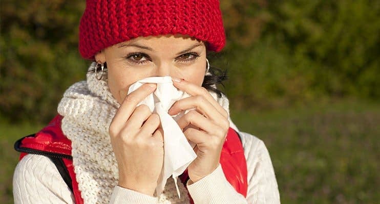 Woman In Red Hat Sneezing Into A Tissue