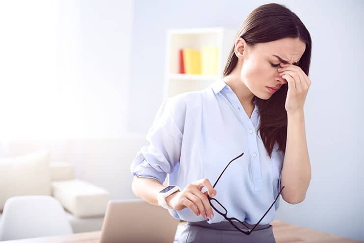 Young Woman Holding The Bridge Of Her Nose Suffering From A Migraine