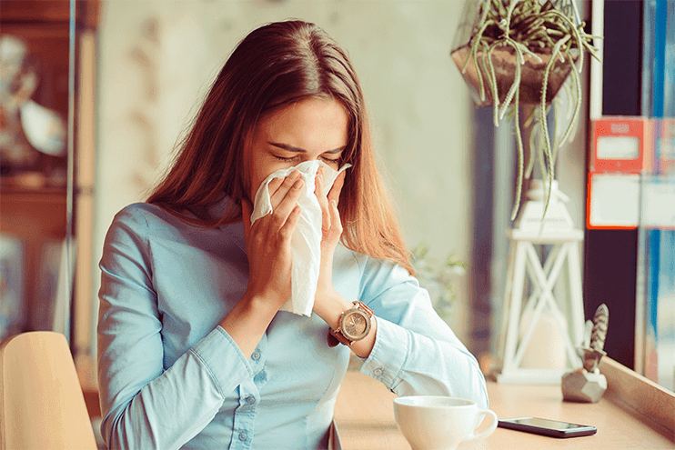 Brown Haired Woman With Allergies Sneezing Into Napkin