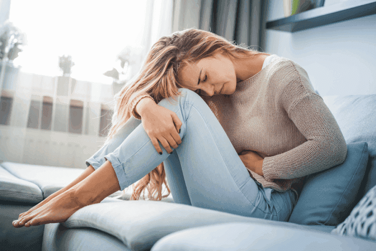 Woman Hunched Over In Pain From Pms Symptoms